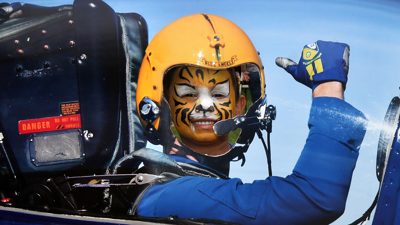 Young boy with painted face poses in airplane